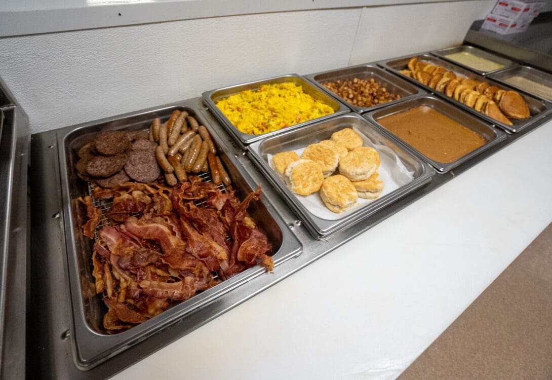 A selection of breakfast food offered in CHH Pecos lodge buffet style, with eggs, bacon, sausages, biscuits and gravy, and pancakes