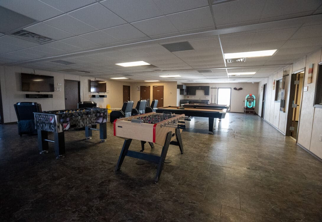 Rec room in CHH Pecos Lodge with two billiards tables and tornado foosball tables and a dedicated lounge area for watching TV