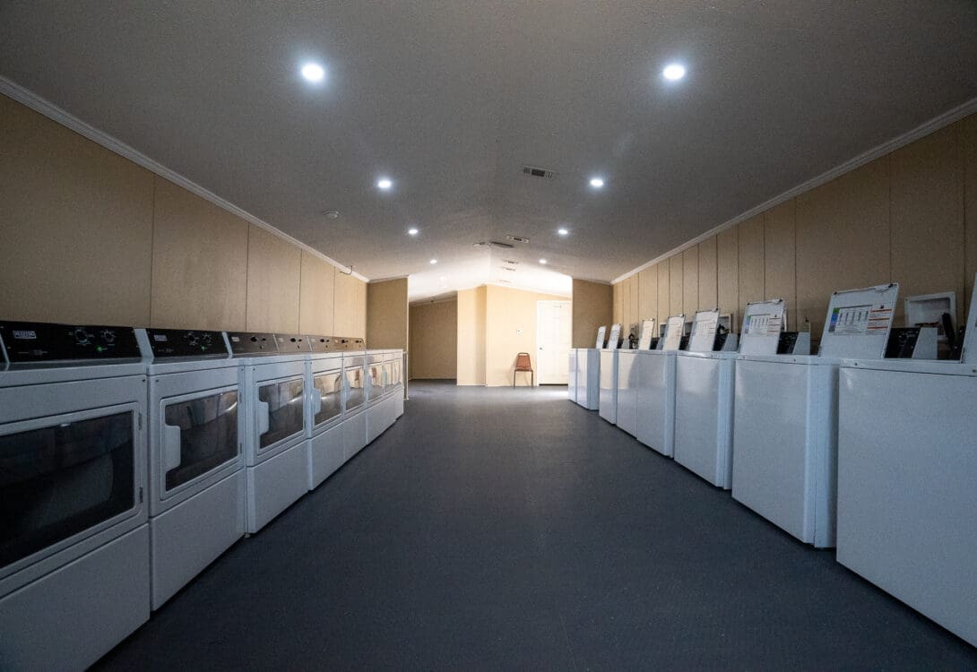 Laundry area in CHH Pecos, wit hseveral washing machines in one side and driers on the other side