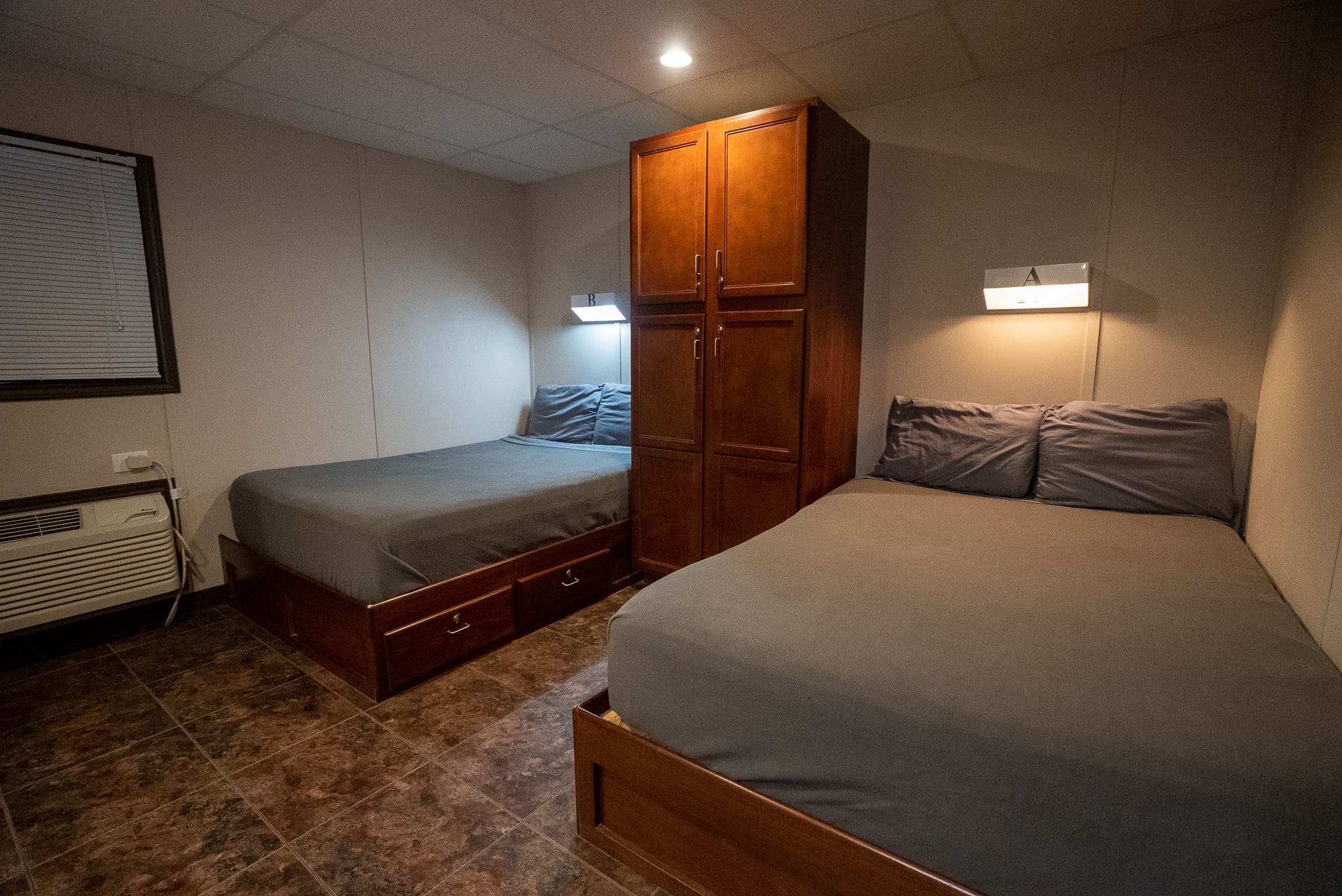 An air conditioned twin-double-room in CHH Pecos with a closet cabinet in between the beds in a tiled floor