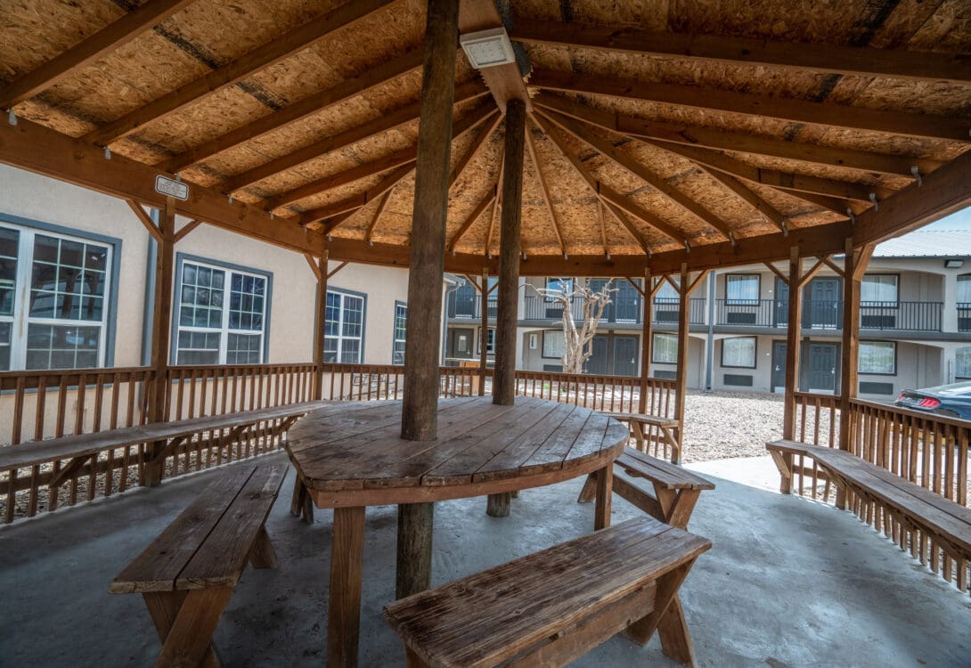 The inside of a wooden gazebo in CHH Big Spring with wooden chairs and tables