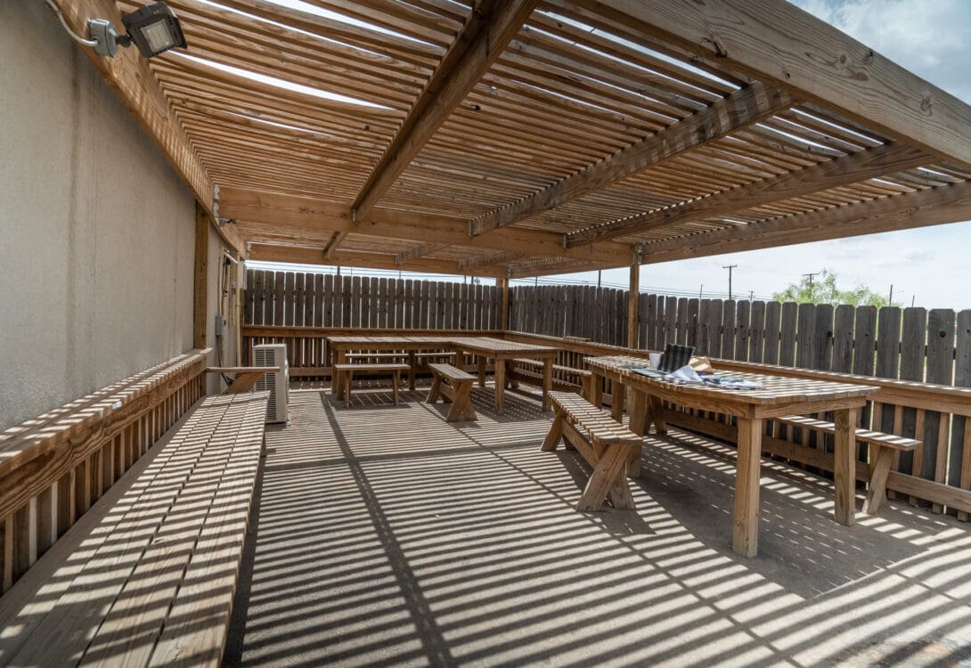 The inside of a wooden pergola in CHH Big Spring with wooden chairs and tables
