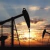 Oil drilling machinery in a silhouette shot on a sunset covered sky as a background