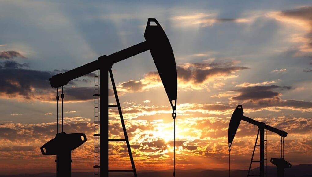 Oil drilling machinery in a silhouette shot on a sunset covered sky as a background