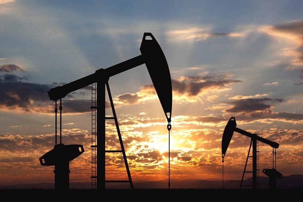 Oil drilling machinery in a silhouette shot on a sunset covered sky as a background