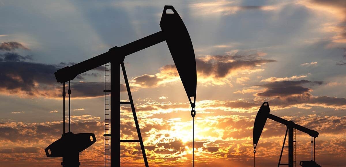 Oil drilling machinery in a silhouette shot on a sunset covered sky as a background