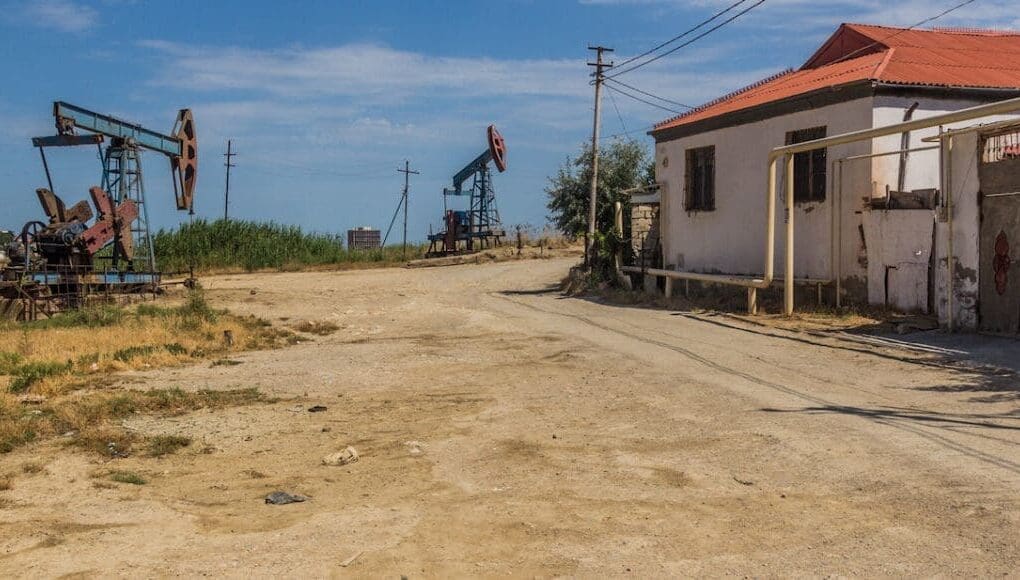 A sample image of oil-field housing with dirt road and oil machineries all around the houses